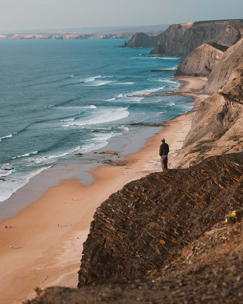vertical shot of a person on a cliff looking at th 2ur8dy4.jpg